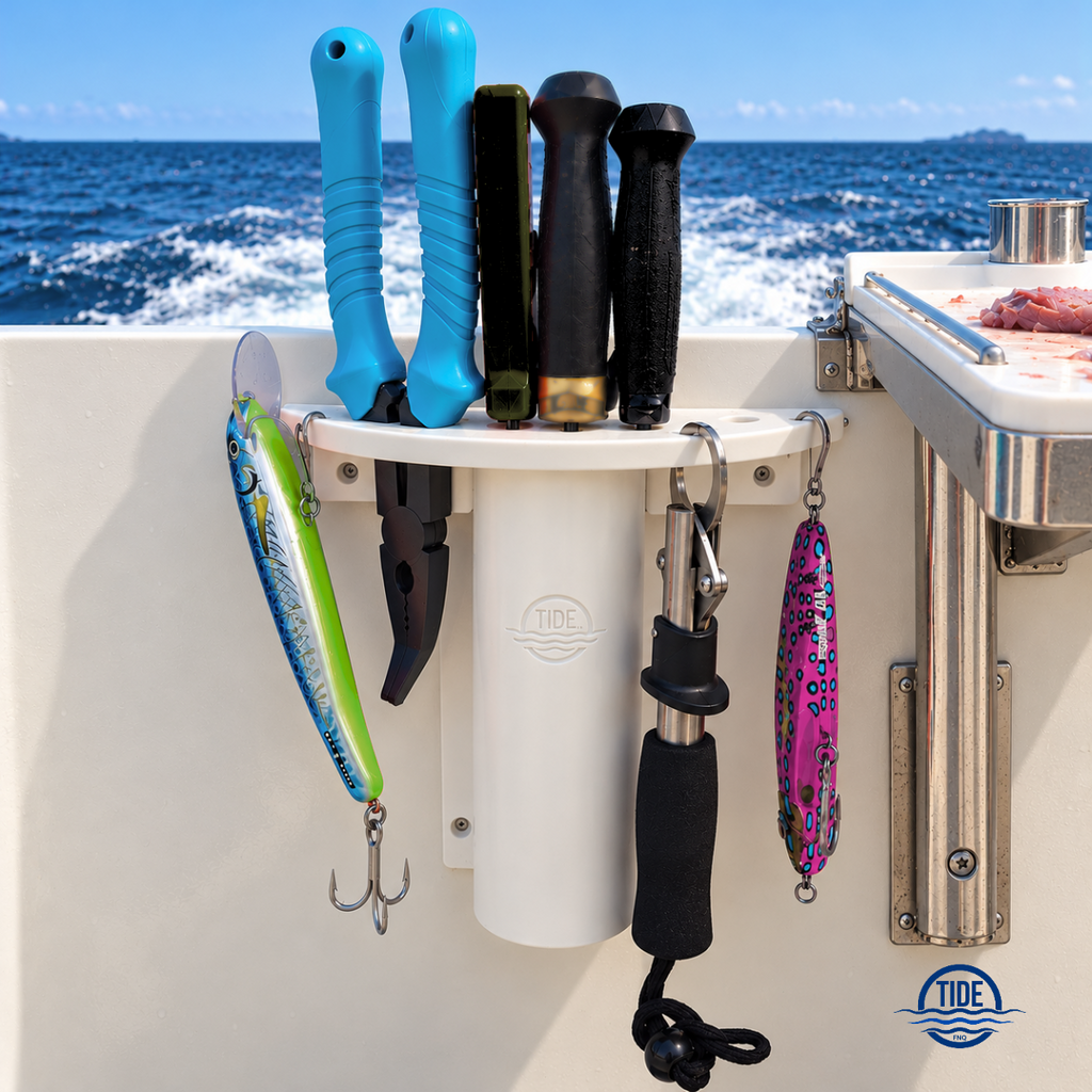A white marine fishing tool holder mounted on a boat's deck, holding fishing tools and several fishing lures, with the ocean in the background.